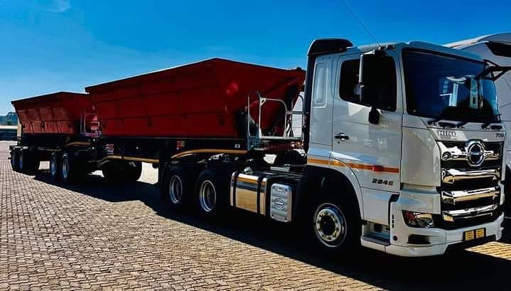 White truck with red side tipper trailers