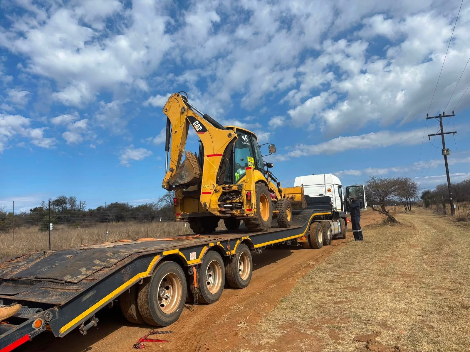 CAT backhoe loader loaded onto a lowbed trailer